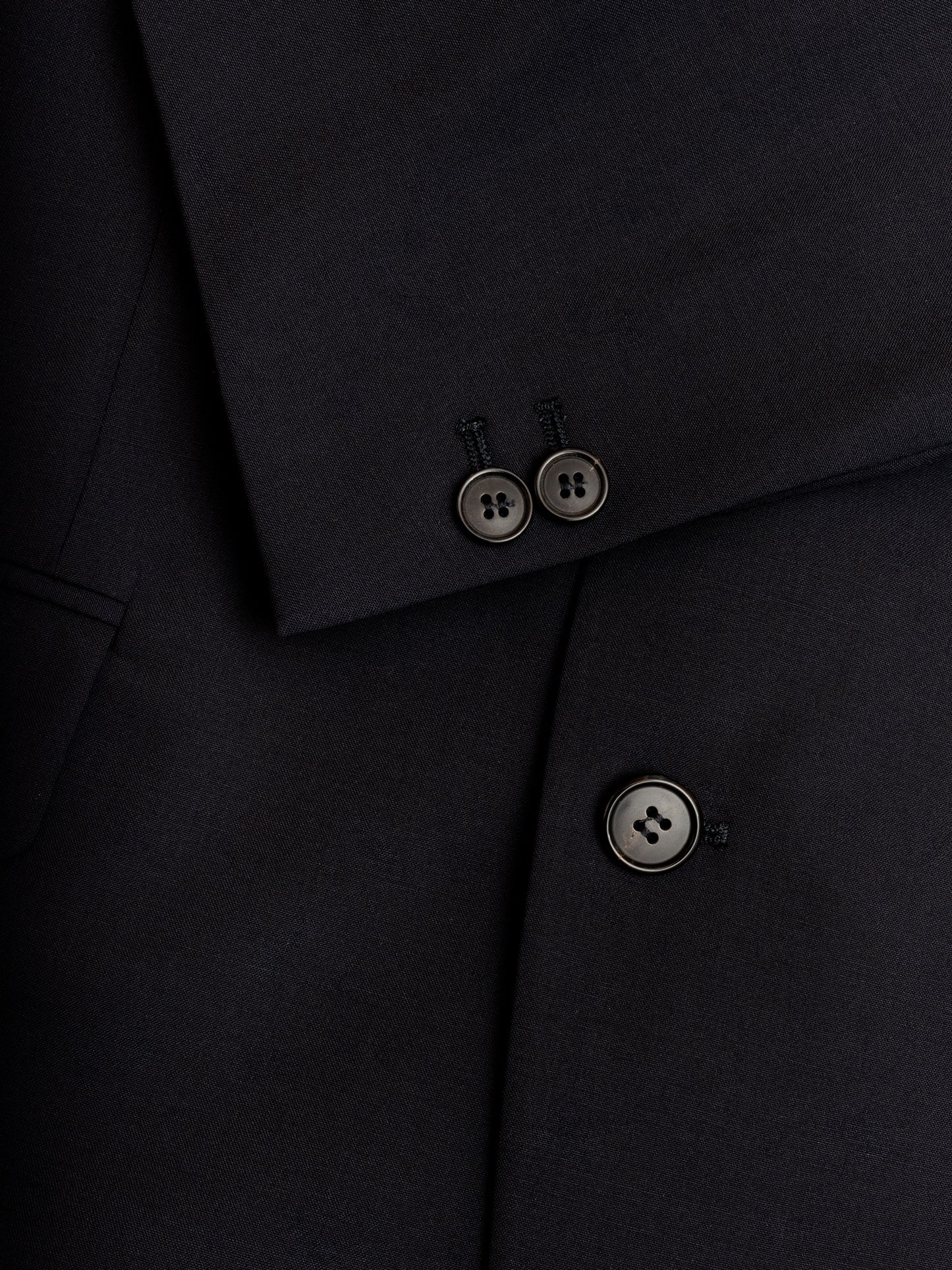 Macro detail of lapel stitch and buttons on Super 120s wool blazer