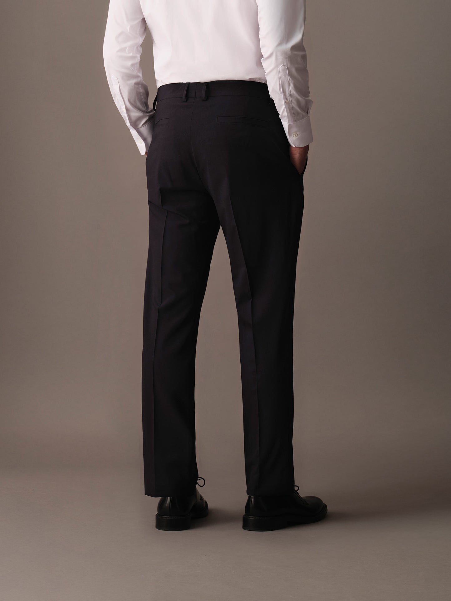 Rear view of refined men’s trousers with welt pockets and clean cutting