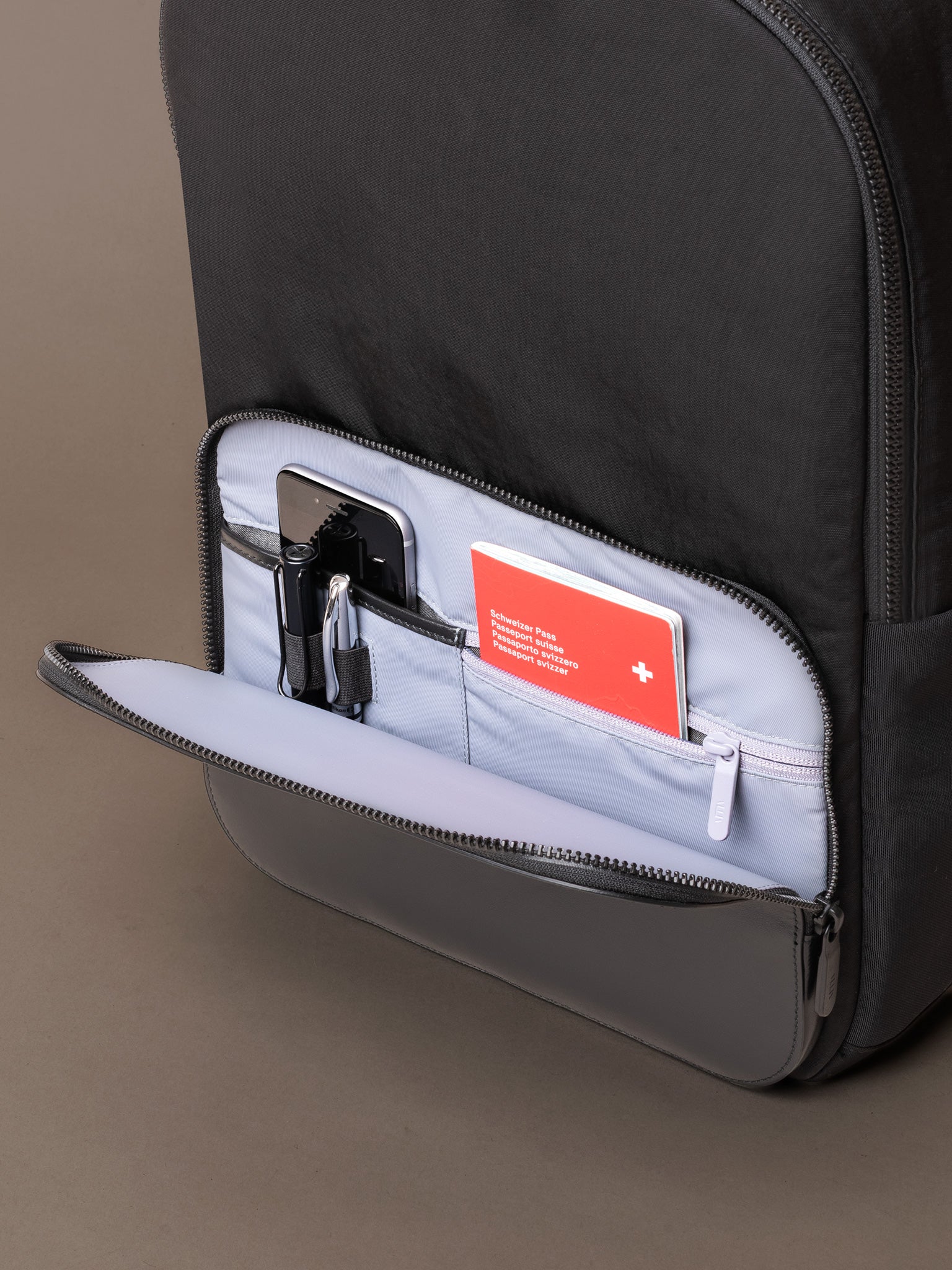 Front zip pocket on The Boardroom Backpack showing organiser slots for travel essentials